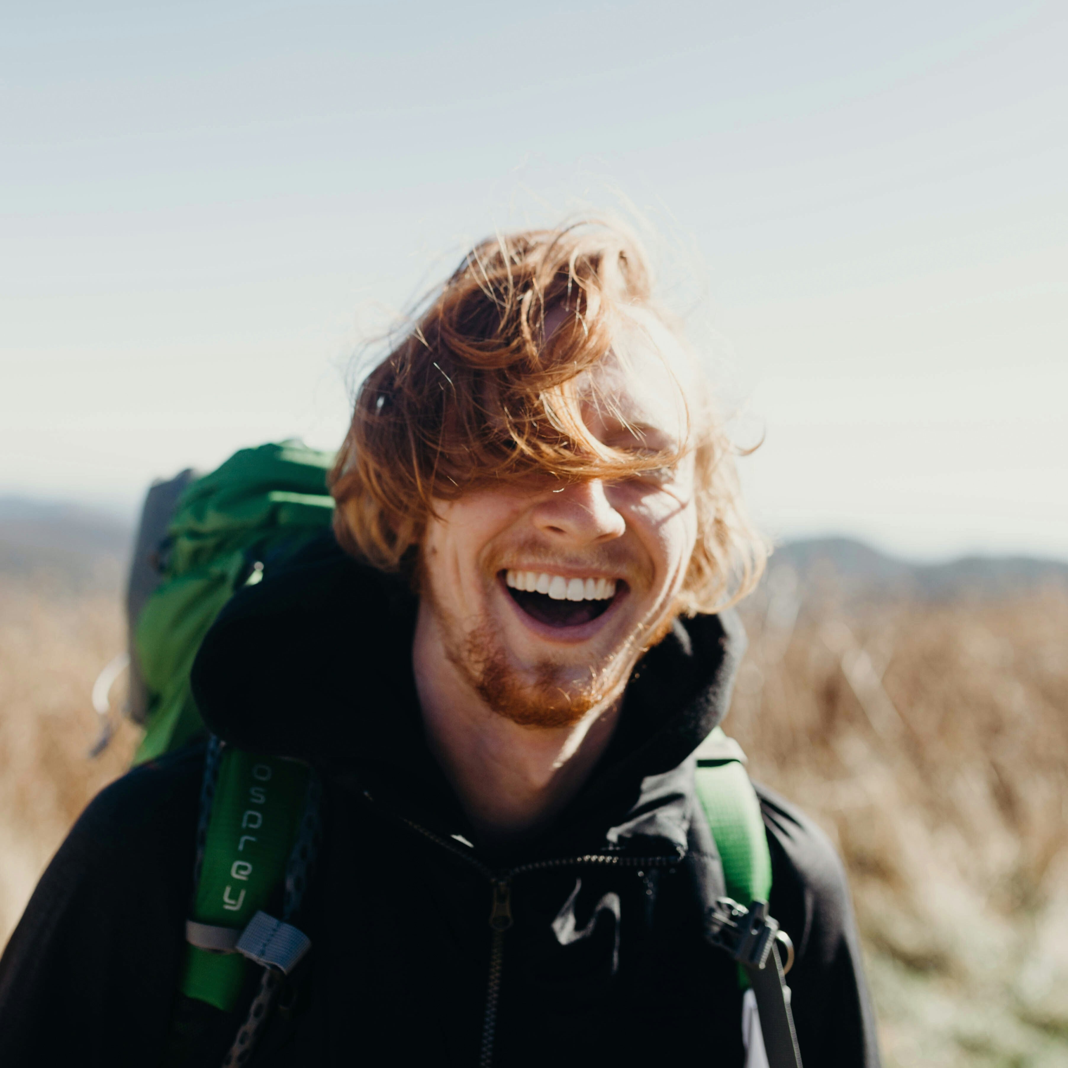 a man with outdoor gear laughing in the wild