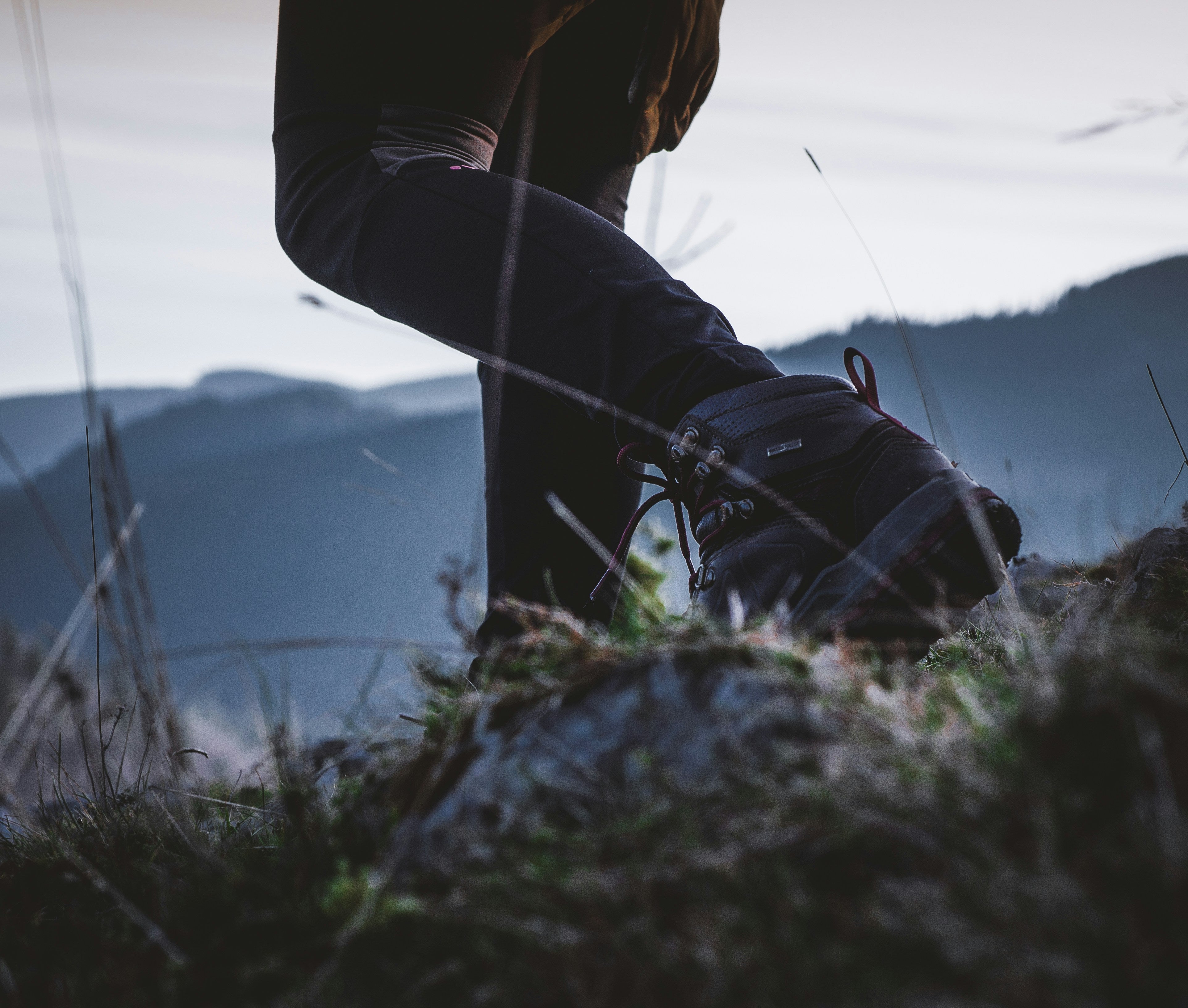 Close-up of hiking boots on a rocky mountain trail at dawn, symbolizing outdoor adventure and freedom